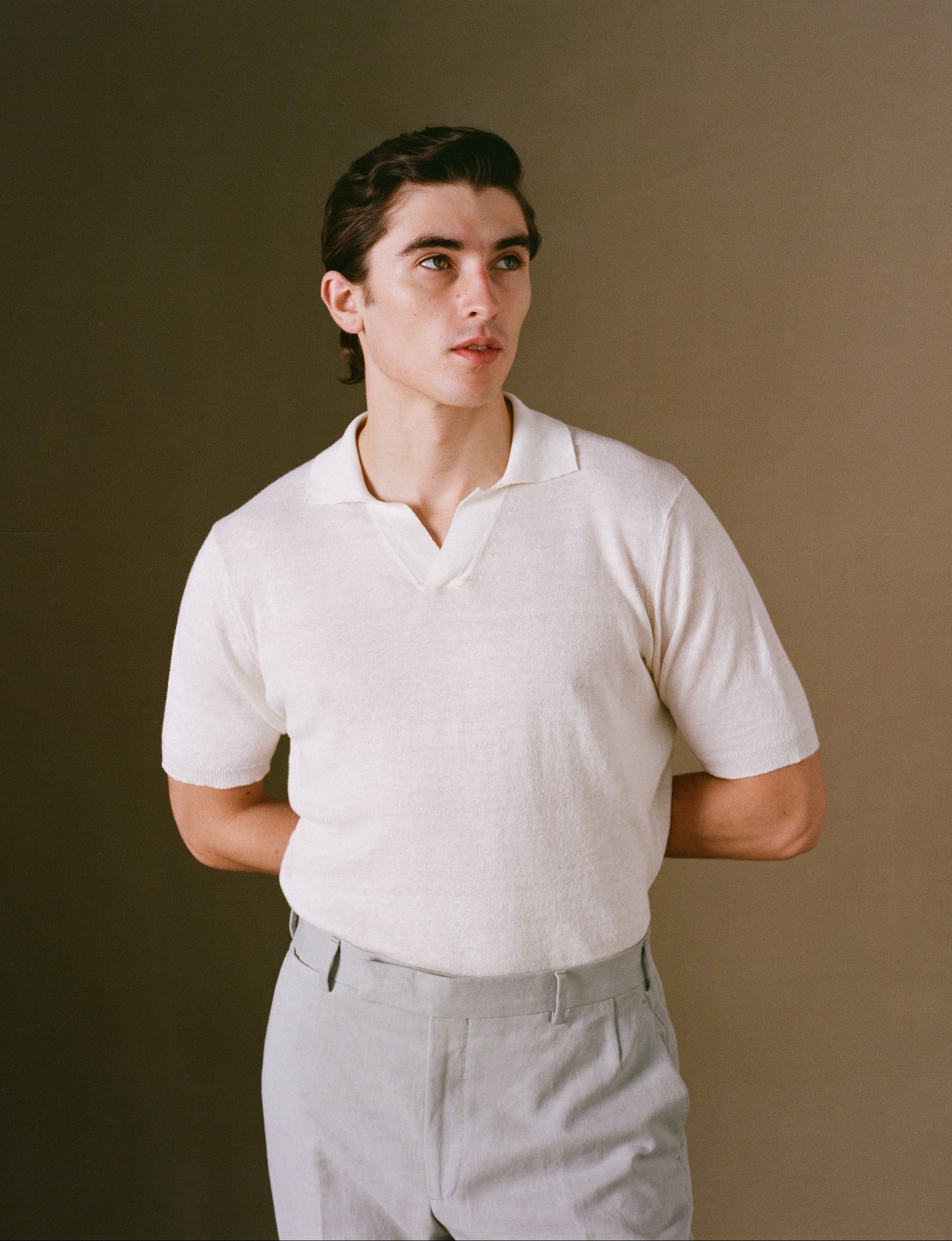 Person wearing a white shirt and gray pants against a plain background