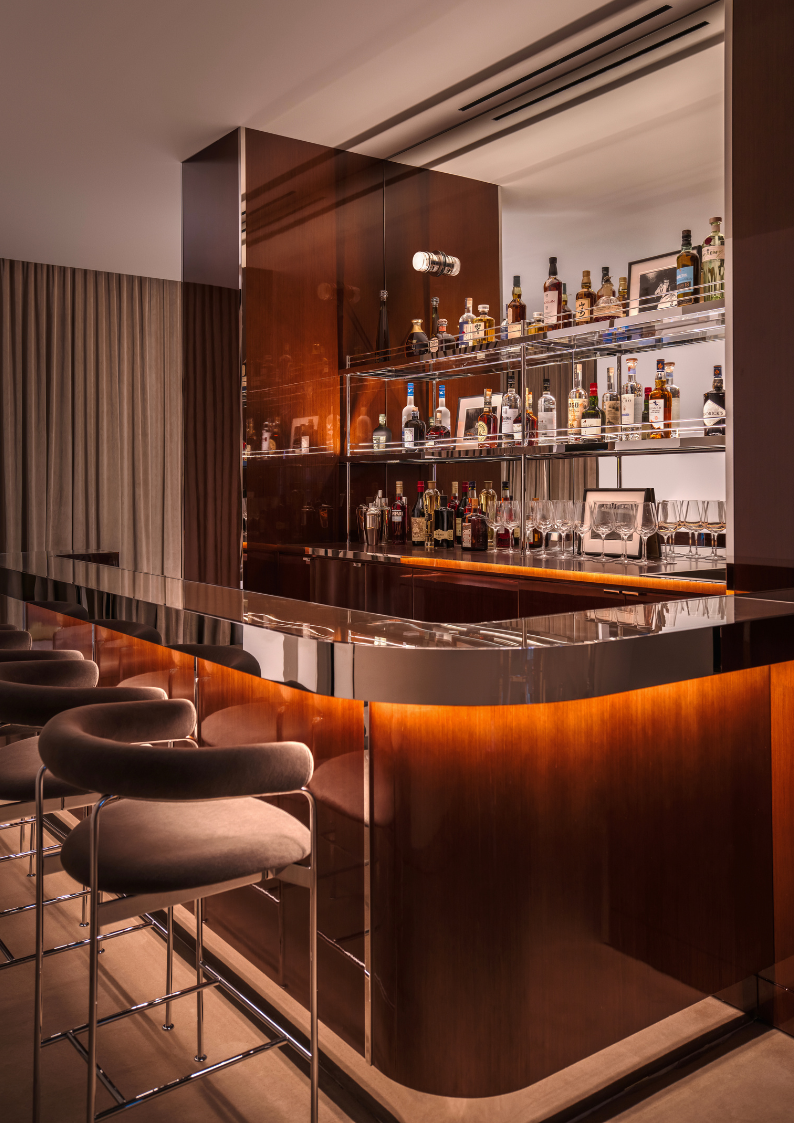 Modern bar interior with shelves of bottles and a curved bar counter.