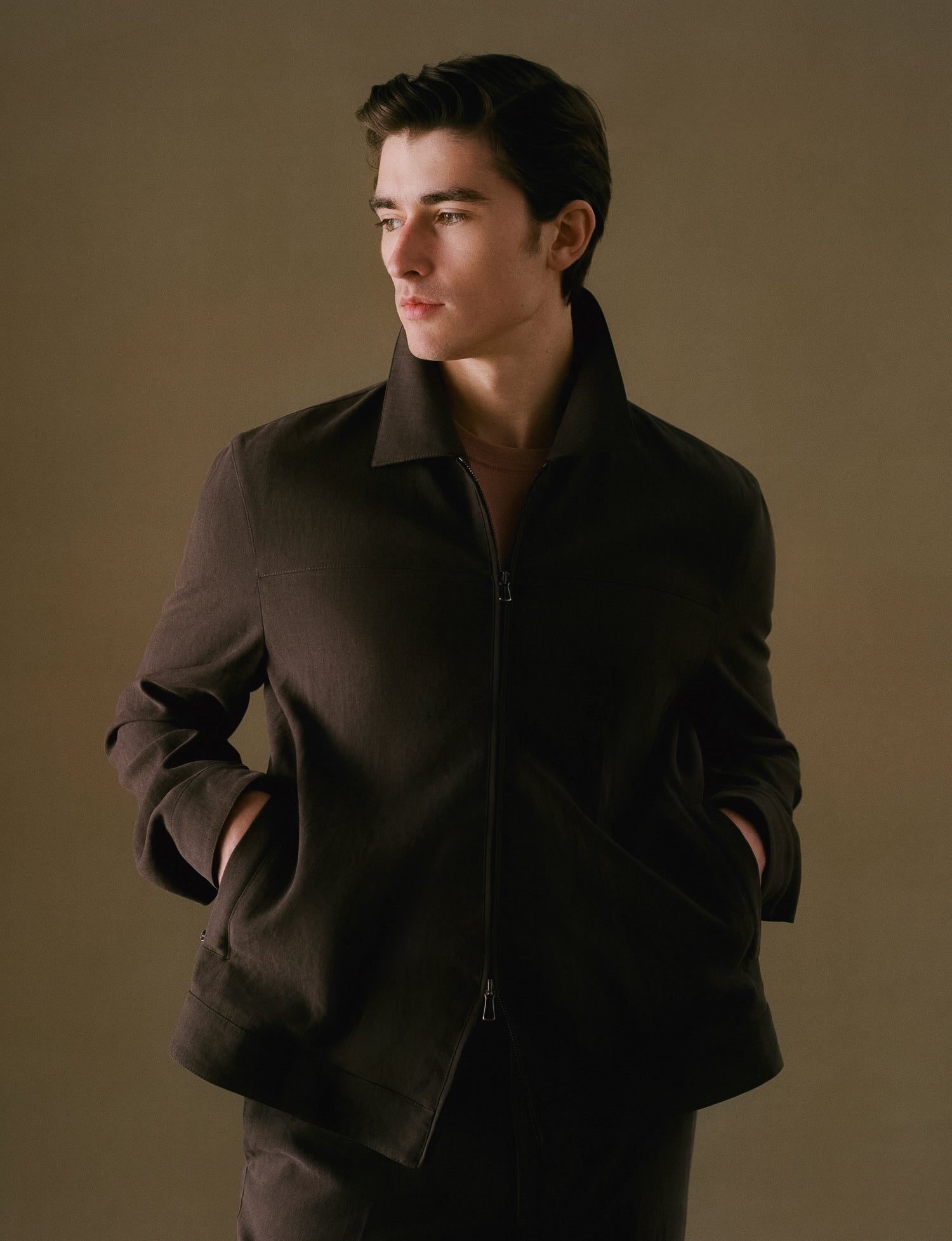 Man wearing a dark brown jacket against a plain background