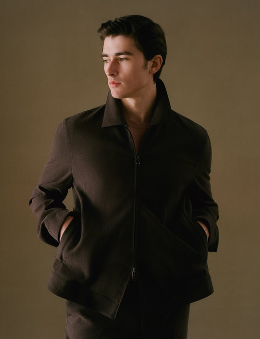 Man wearing a dark brown jacket against a plain background