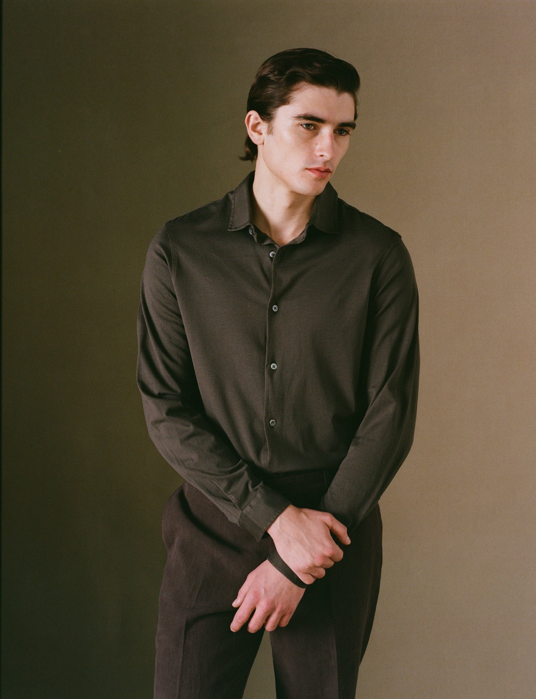 Man wearing a black shirt against a brown background