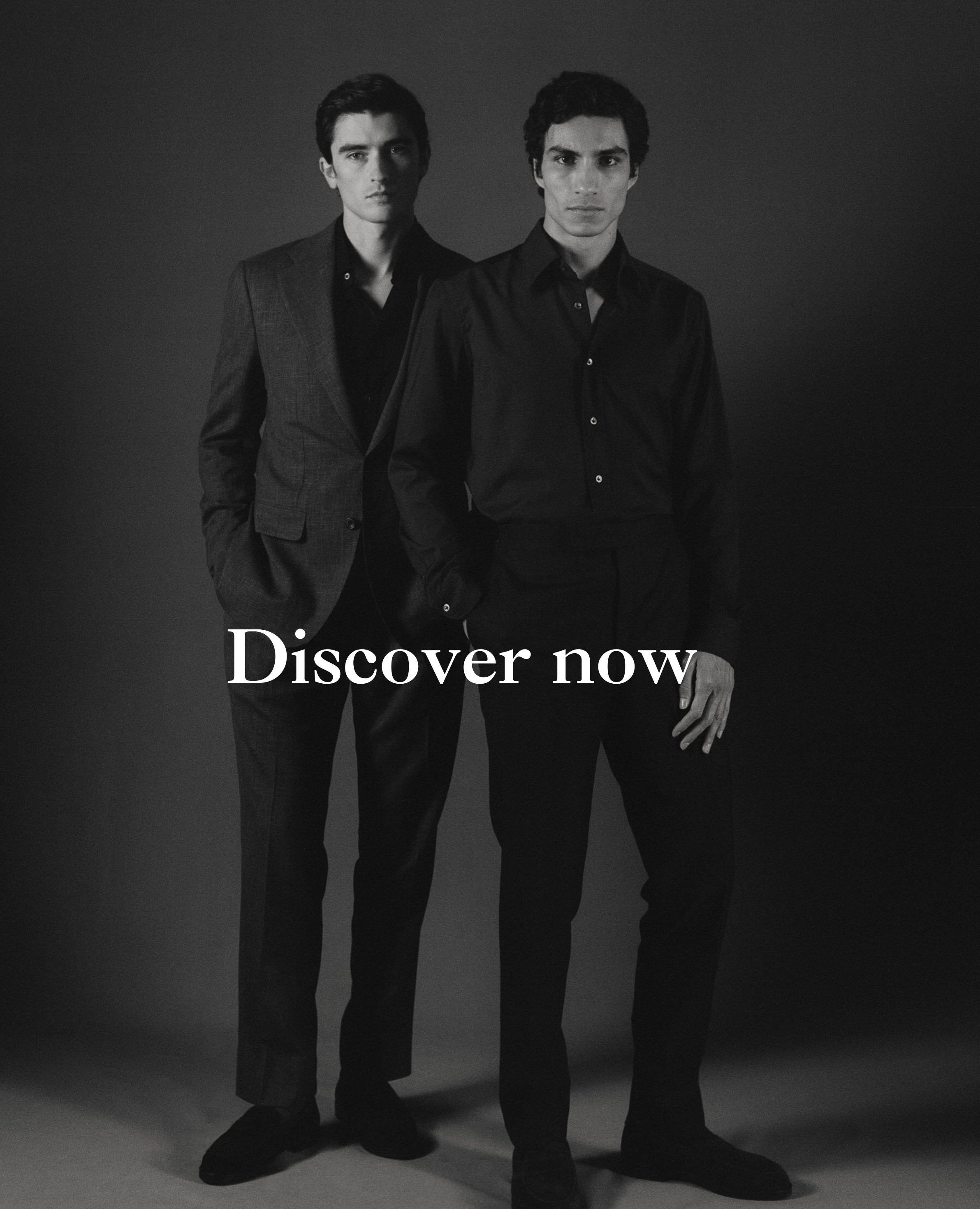 Two men in formal attire standing against a dark background with 'Discover now' text.